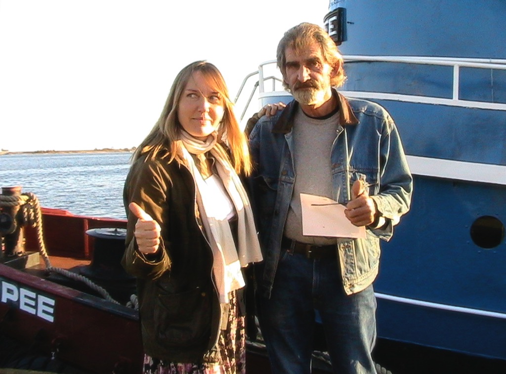 Two people standing on deck of tugboat